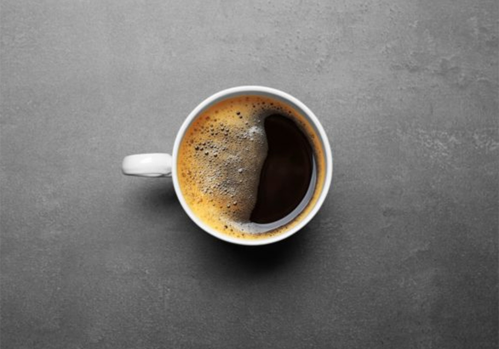 A képen egy csésze crema nélküli, vizes, rossz minőségű kávé fotója látható.